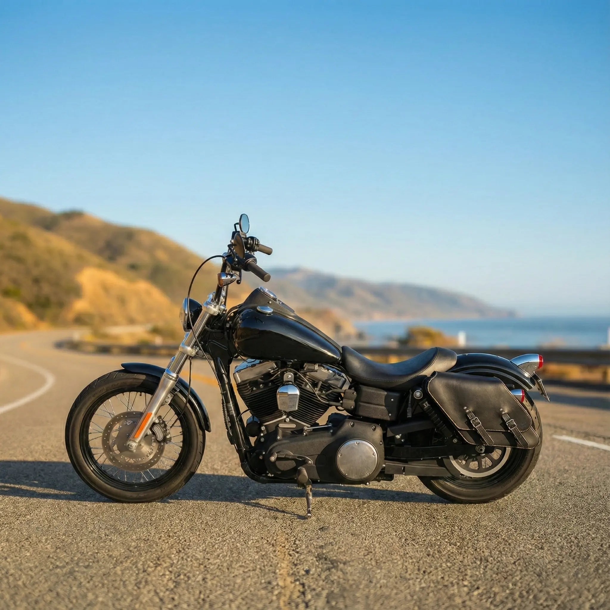 Black motorcycle on a road with a scenic background of mountains and ocean.
