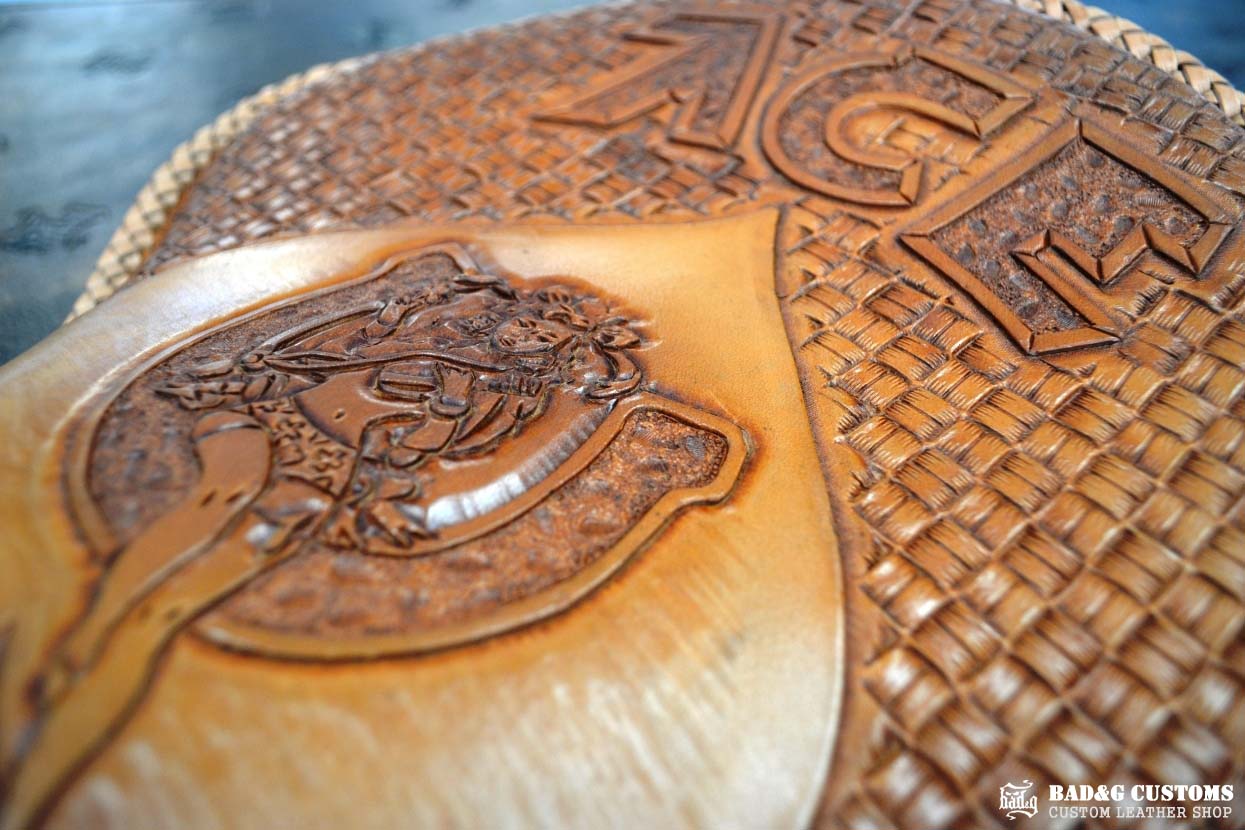 "ACE Pin-Up Girl" design hand tooled and braided on a chopper solo seat. Veg tan leather with kangaroo lace.