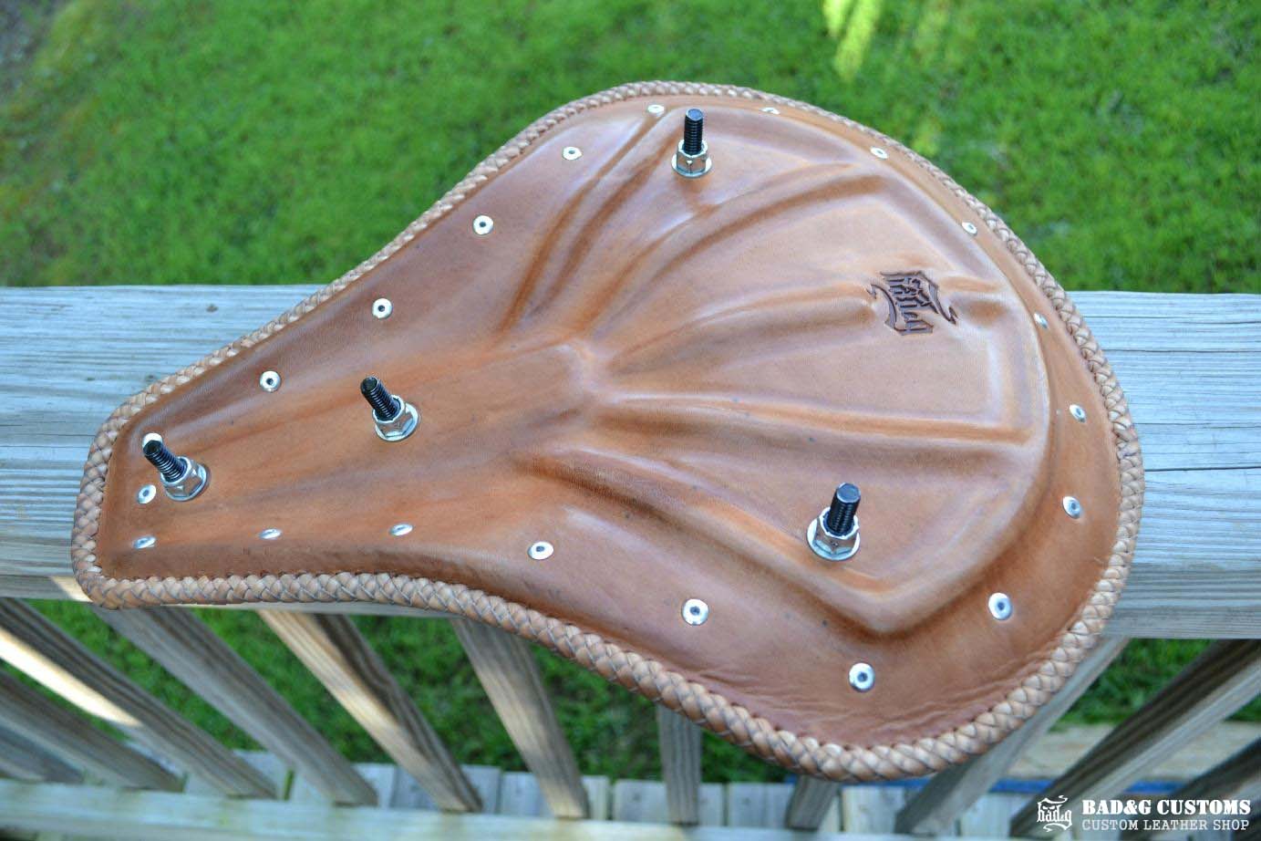 "CROSS" design hand tooled and braided on a chopper solo seat. Brown Veg tan leather with kangaroo lace.